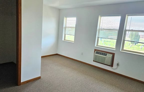 A room with a window and a wall-mounted air conditioner unit.