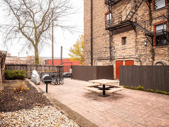 A brick building with a fire escape and a picnic table in front.