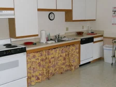 A kitchen with a white oven and a clock on the wall.