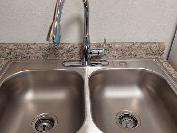A stainless steel double sink with a chrome faucet.