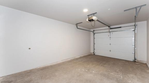 A white wall with a garage door opener and a light fixture.