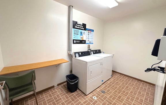 A room with a washing machine and a chair.