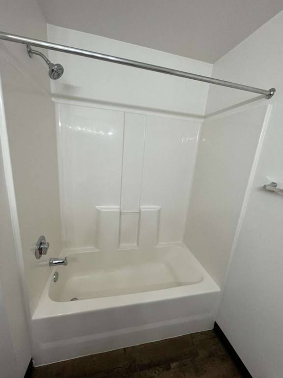 a white bathtub with a shower rod above it