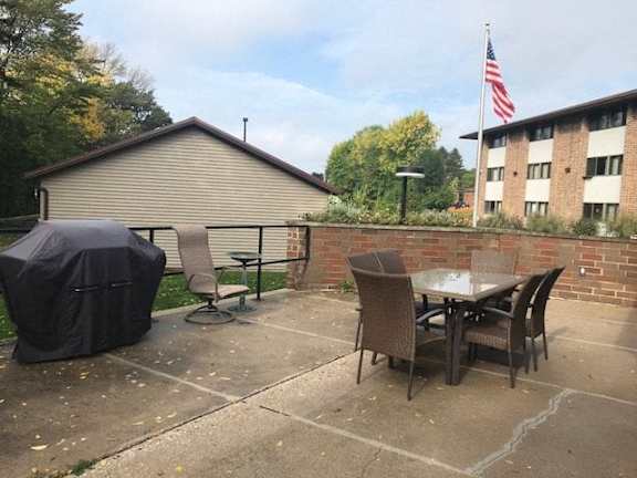 A patio with a table and chairs and a flag on a building.