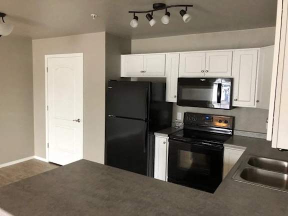 A kitchen with black appliances and white cabinets.