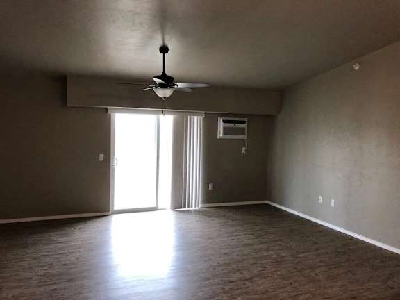 A room with a ceiling fan and a door leading to a hallway.