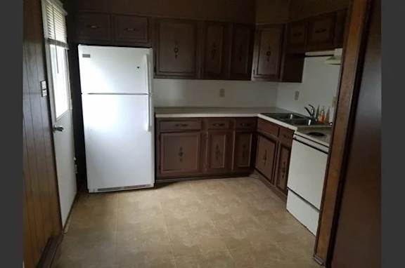 A kitchen with a white refrigerator and brown cabinets.