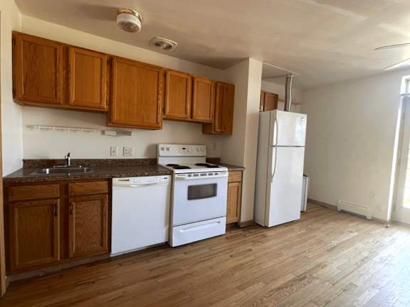 A kitchen with white appliances and wooden cabinets.