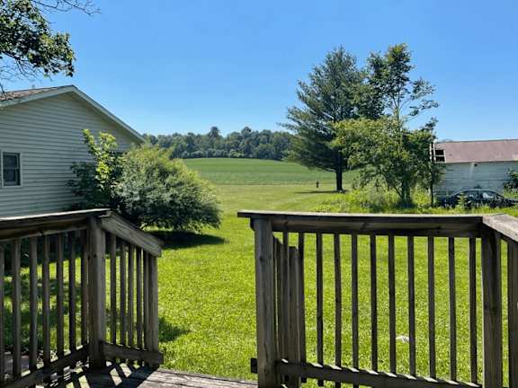 A wooden deck overlooks a lush green field.