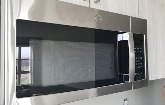 A stainless steel microwave oven with a digital display and control panel.