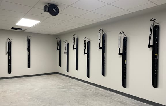 A wall of black exercise equipment in a white room.