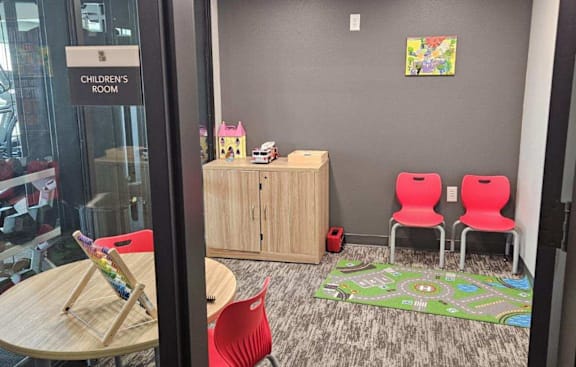 A children's room with a play mat and two red chairs.