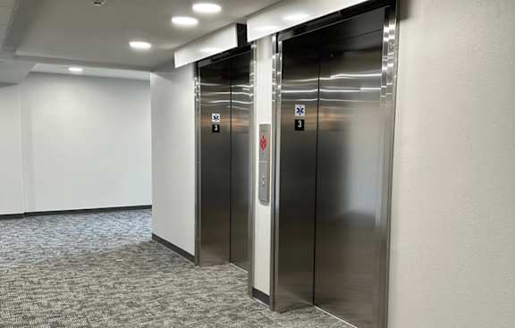 Two stainless steel elevators in a hallway.