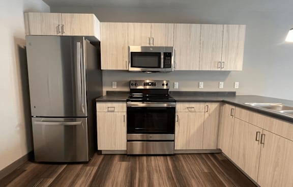 A modern kitchen with a refrigerator, oven, and microwave.
