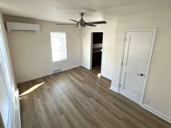 A room with a ceiling fan and wooden flooring.