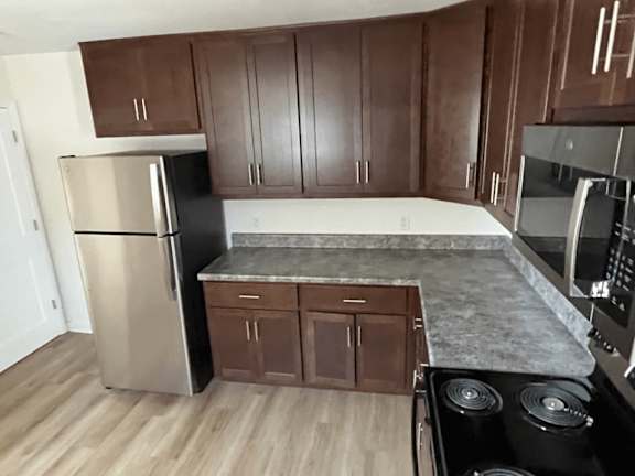 A kitchen with a stainless steel refrigerator and wooden cabinets.