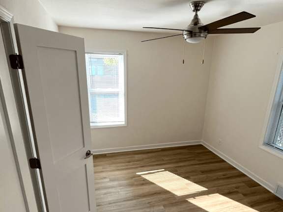A room with a ceiling fan and a door.