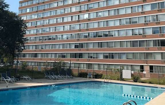 A swimming pool in front of a tall brick building.
