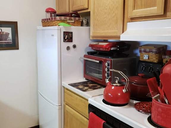 A red kettle is on a stove in a kitchen.