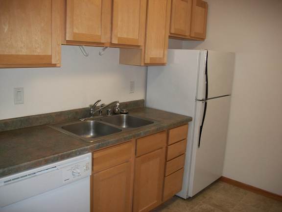 A kitchen with wooden cabinets and a white refrigerator.