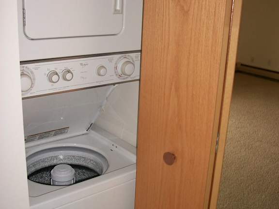 A white dishwasher with a grey drain plug is in a kitchen.