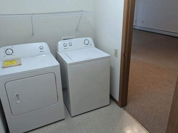 Two white front loading washing machines in a laundry room.