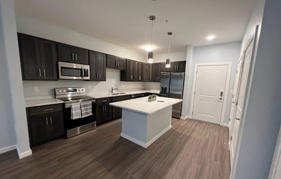 A kitchen with dark brown cabinets and a white island.