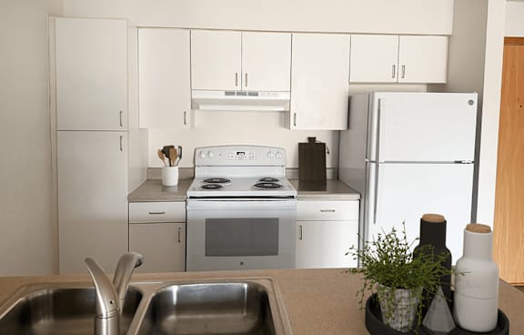 A white kitchen with a stove, oven, and refrigerator.