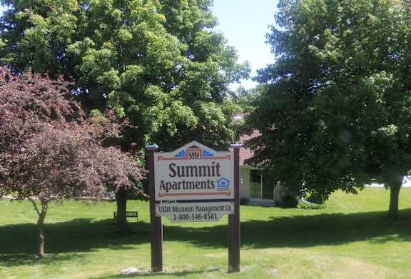 A sign for Summit Apartments is in front of a green lawn.