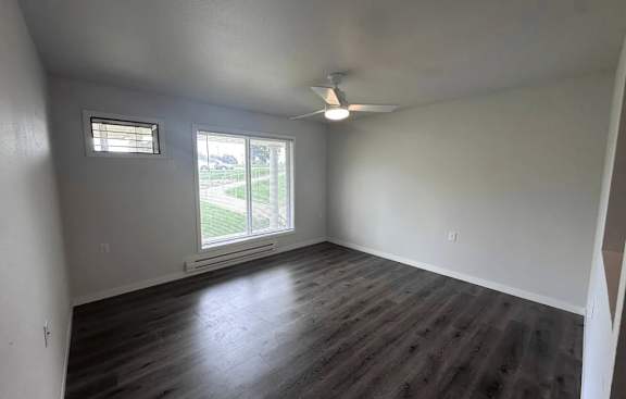 A room with a ceiling fan and a window with blinds.