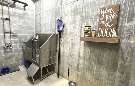 A dog kennel is in a concrete room with a sign that says "you, me and the dogs".
