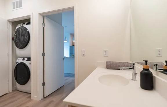 A white bathroom with a washer and dryer in the doorway.