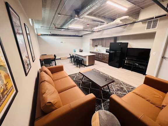 A living room with a brown couch and a black television.