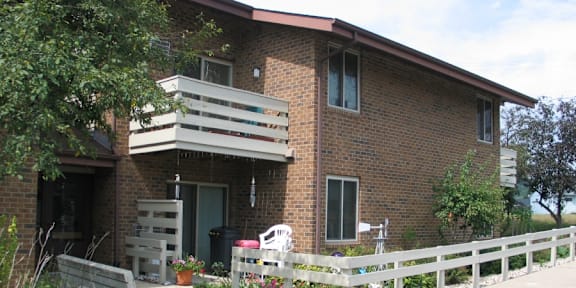 A red brick house with a white fence in front.
