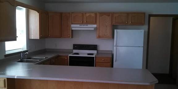 A kitchen with wooden cabinets and a white refrigerator.