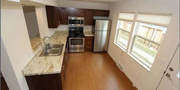 A kitchen with a stove, oven, refrigerator, and sink.