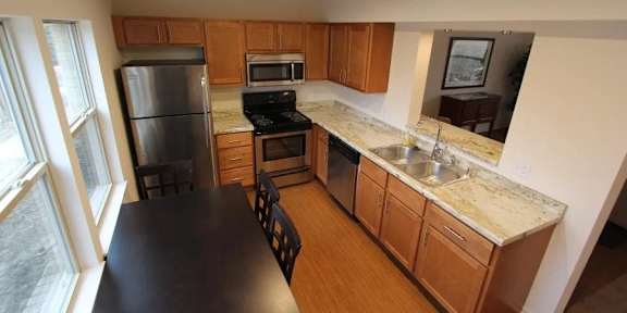 A kitchen with wooden cabinets and a black counter.