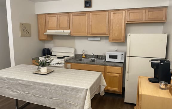 A kitchen with a table and a fridge.