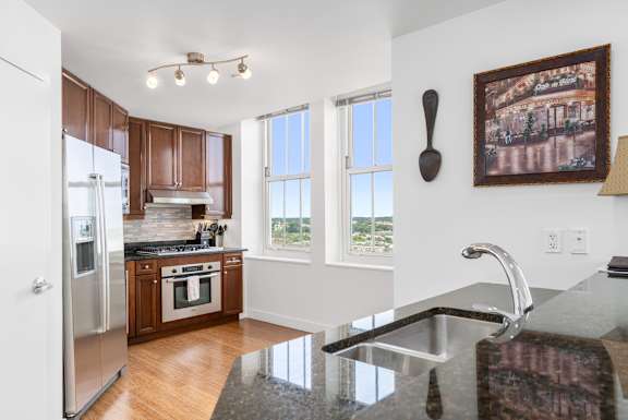 A kitchen with a granite counter top and a painting hanging on the wall.