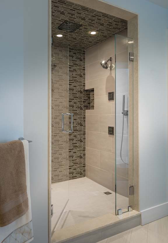 A bathroom with a glass shower door and a brown towel hanging on the wall.