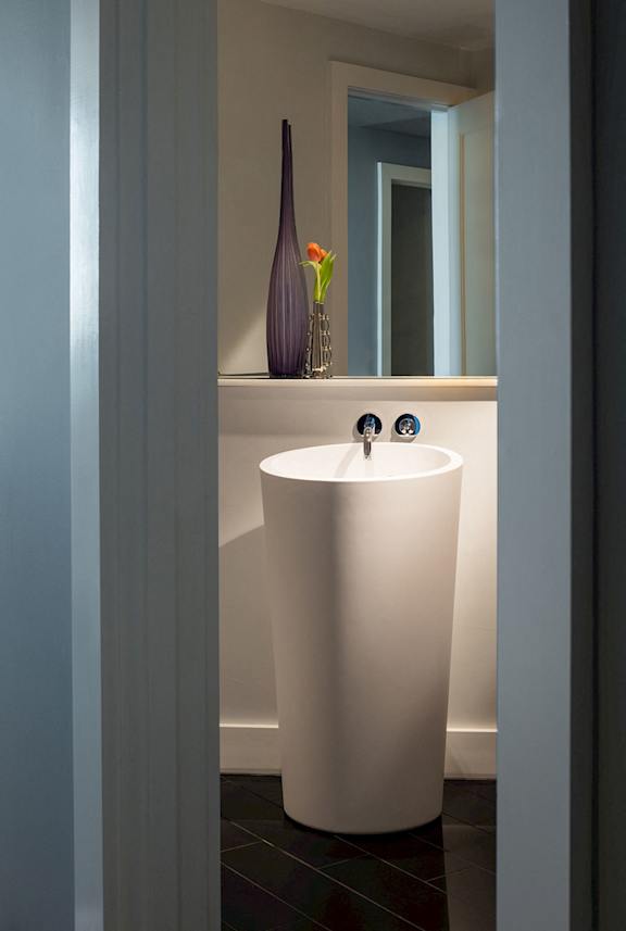 A white pedestal sink with a vase of flowers on top of it.