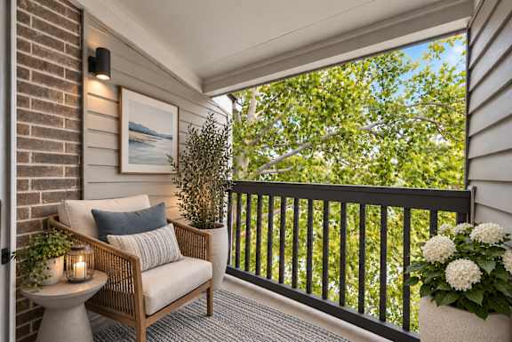 A balcony with a chair, table, and plants.