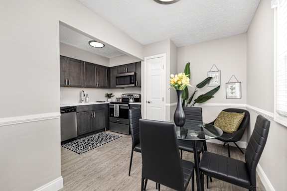 A kitchen with a dining table and chairs.