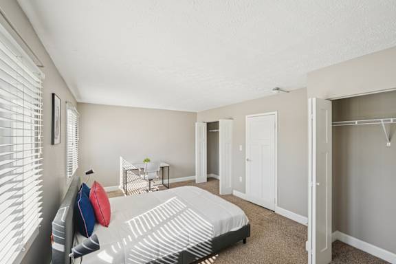 A bedroom with a bed, a chair, and a small table with a plant on it.