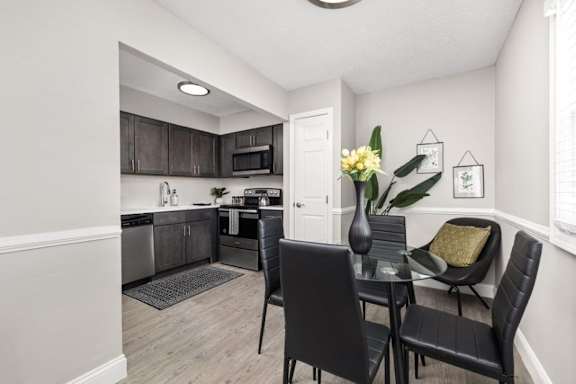 A kitchen with a dining table and chairs.