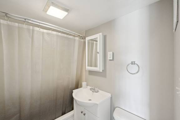 A white bathroom with a sink, toilet and shower curtain.