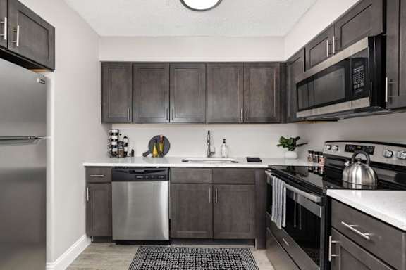 A kitchen with dark wood cabinets and stainless steel appliances.