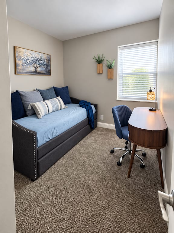 A bedroom with a bed, desk, and chair.