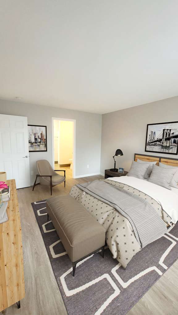 A bedroom with a large bed and a chair.