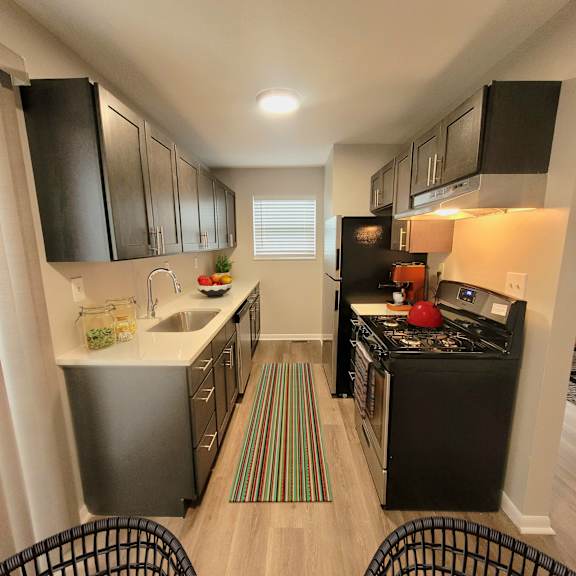 A kitchen with black cabinets and a black stove top oven.